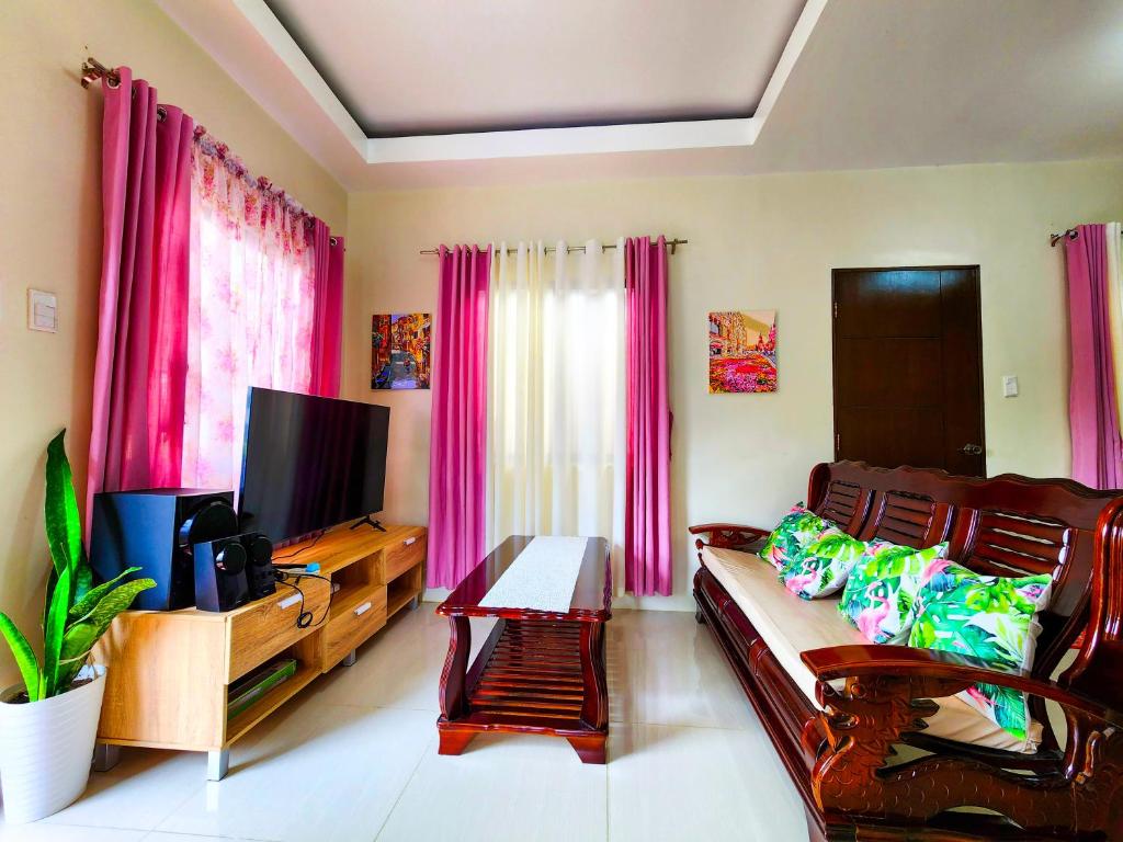 sala de estar con sofá y TV de pantalla plana en Serene 2BR Escape: Poolside Bliss in Iloilo City, en Iloilo City