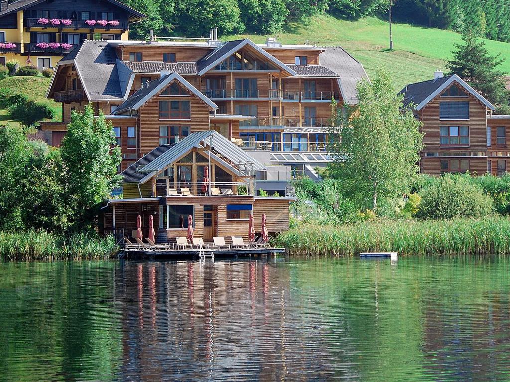 uma casa grande ao lado de um lago em Appartementhotel am Weissensee em Weissensee