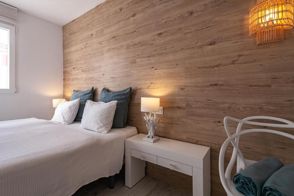 ein Schlafzimmer mit einem weißen Bett und einer Holzwand in der Unterkunft Apartment BEACH & RELAX in Port de Pollença