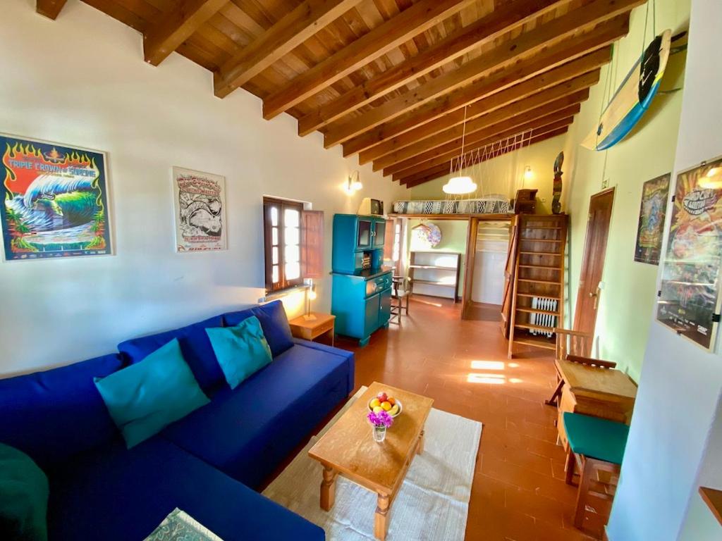 Una sala de estar con un sofá azul y una mesa. en Da Silva Surfcamp- Terrassenzimmer mit Frühstück, en Lourinhã