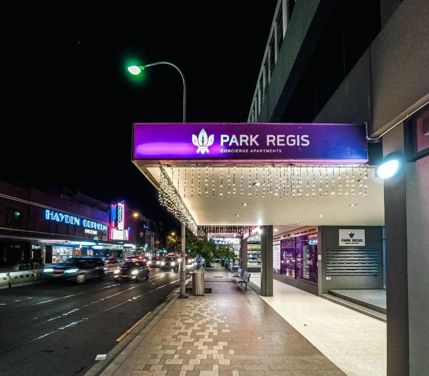 a building with a park fees sign at night at Park Regis Concierge Apartments in Sydney