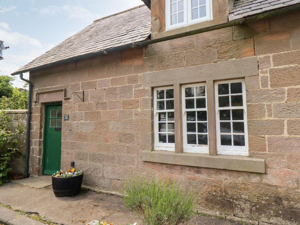 une maison en briques avec une porte verte et une fenêtre dans l'établissement Cherry Tree Cottage, à Embleton