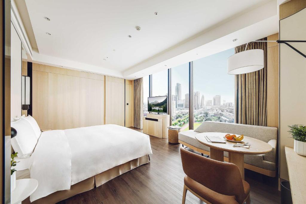 a hotel room with a large bed and a table at Jasper Young Hotel Banqiao in Taipei