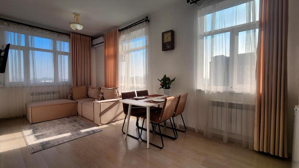 a living room with a table and chairs and windows at Assalom Apartment 6 in Tashkent