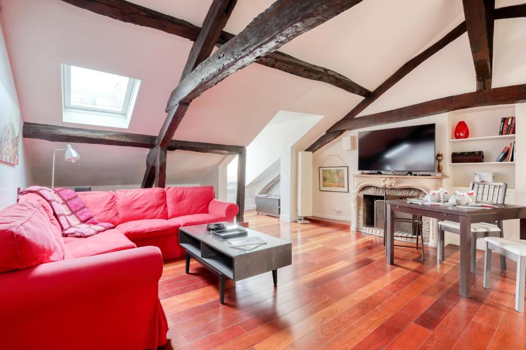 uma sala de estar com um sofá vermelho e uma mesa em Nid d'Artiste - 5min à pied du château em Versailles
