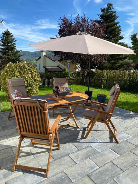 a wooden table and two chairs and an umbrella at Ferienhaus Glückspilz beim Hennesee in Meschede