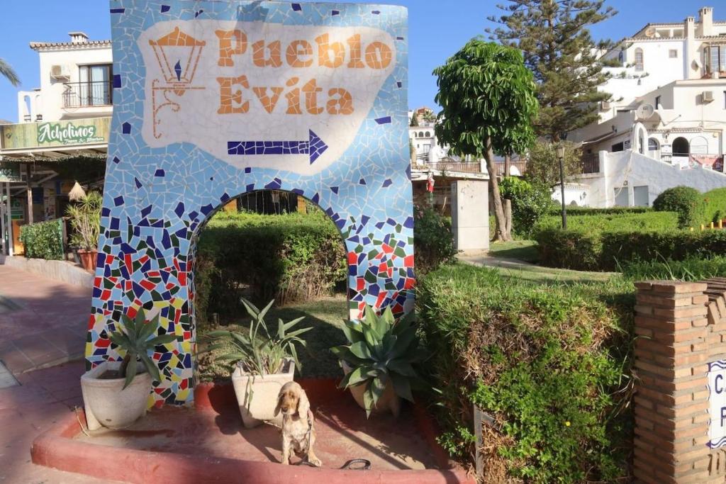 a dog sitting in front of a building with a sign at Apartamento En Pueblo Evita Con Piscina Y Terraza in Benalmadena Costa