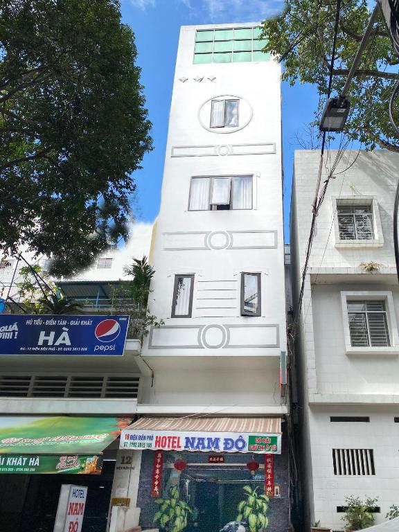 a tall white building with a shop in front of it at NAM ĐÔ HOTEL Chợ Cổ Bến Ninh Kiều in Can Tho