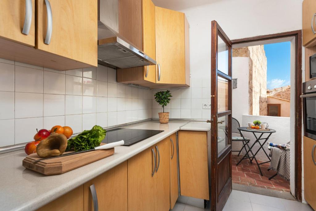 a kitchen with wooden cabinets and a bowl of vegetables on the counter at Sunset apartment Es Celler in Alcudia