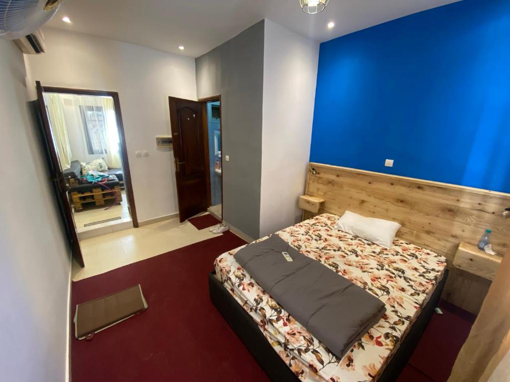 a bedroom with a bed and a blue wall at Studio privé meublé et équipé in Dakar