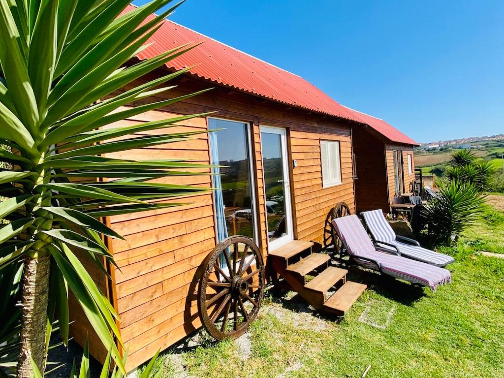 a wooden cabin with a bench and a chair at Tiny House Eloá in Lourinhã