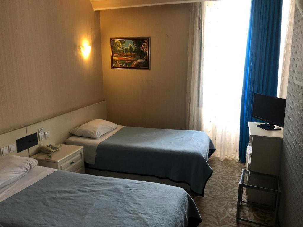 een hotelkamer met 2 bedden en een televisie bij YILDIZ HOTEL in Altındağ