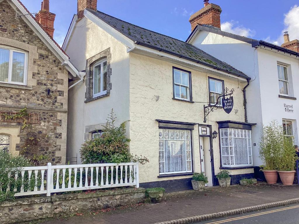 una casa blanca con una valla blanca en una calle en The Old Lace Shop, en Seaton