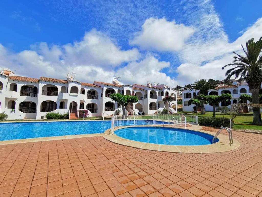 a resort with a swimming pool in front of a building at Apartamento en Son Bou cerca de la playa in Son Bou