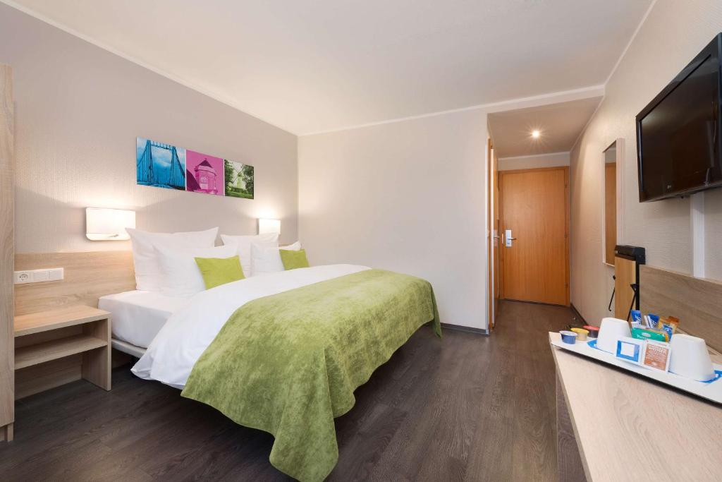 ein Hotelzimmer mit einem Bett und einem Flachbild-TV in der Unterkunft Hotel Dusseldorf Krefeld Affiliated by Meliá in Krefeld