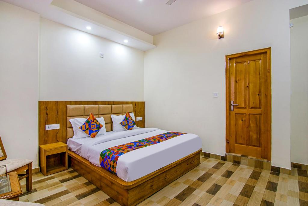 a bedroom with a bed and a wooden door at FabHotel Himalayan Park in Bajaura