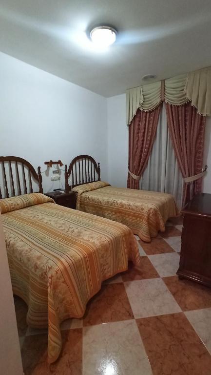 two beds in a room with a checker floor at Hostal Algaidas in Villanueva de Algaidas