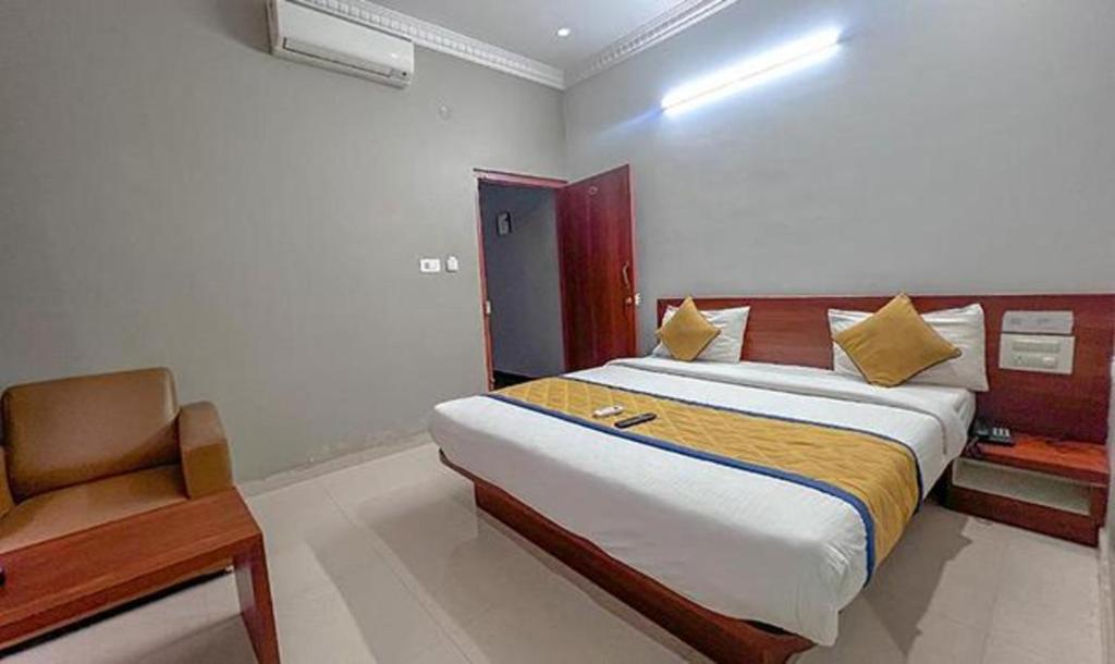 a bedroom with a bed and a chair in it at FabHotel Gateway Suites in Bangalore