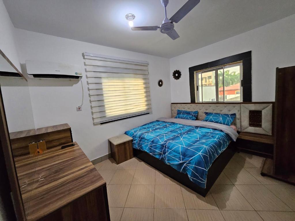 a bedroom with a bed with a blue comforter and a window at Private-room with washroom in spintex, Accra in Accra