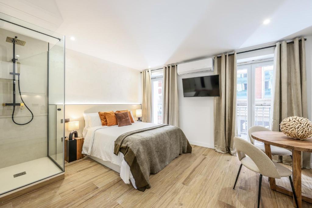 a bedroom with a bed and a table and a shower at Estudio funcional Plaza del Callao in Madrid
