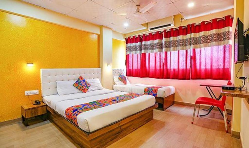 FabExpress Dream Inn في مومباي: غرفة نوم بسريرين وستارة حمراء