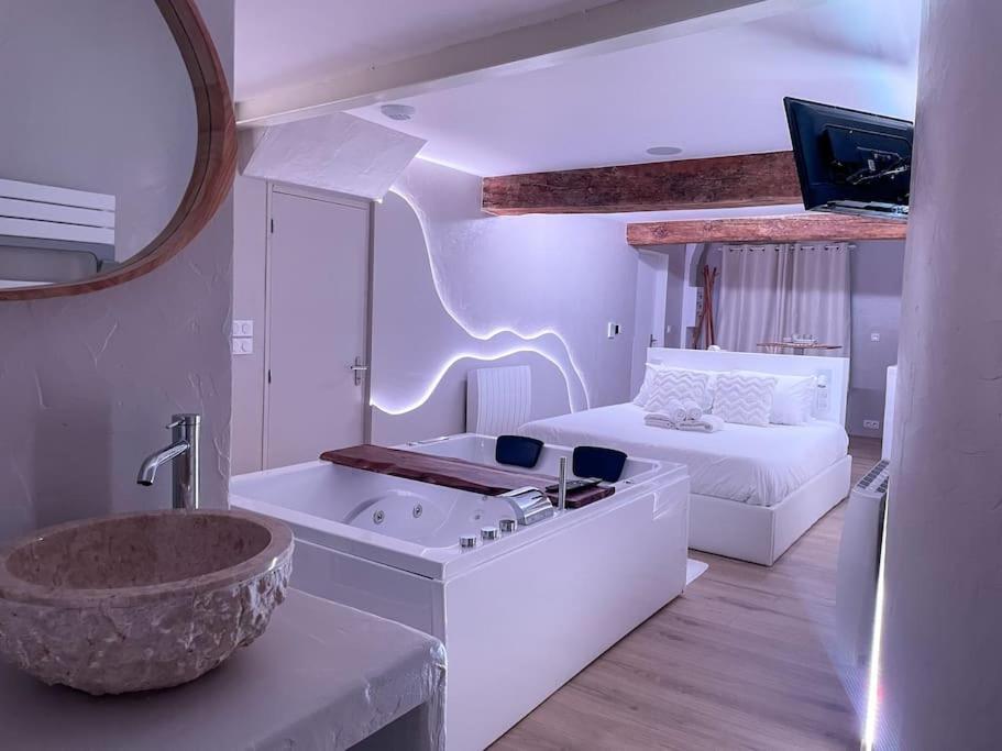 a bathroom with a tub and a bedroom with a bed at À la folie - Loft &amp; Spa in Montrevault