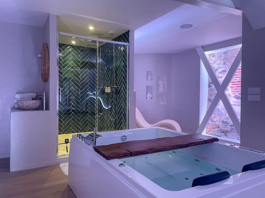 a white bathroom with a tub and a window at À la folie - Loft &amp; Spa in Montrevault