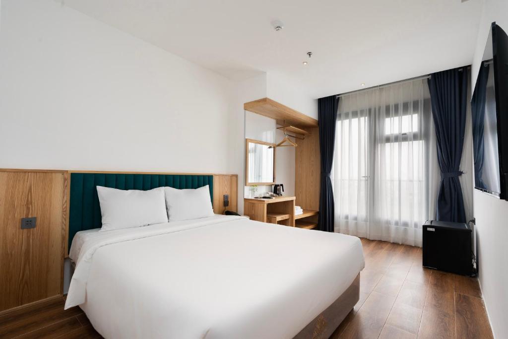 una camera da letto con un grande letto bianco e una finestra di Haven Hut Riverside Hotel ad Ho Chi Minh