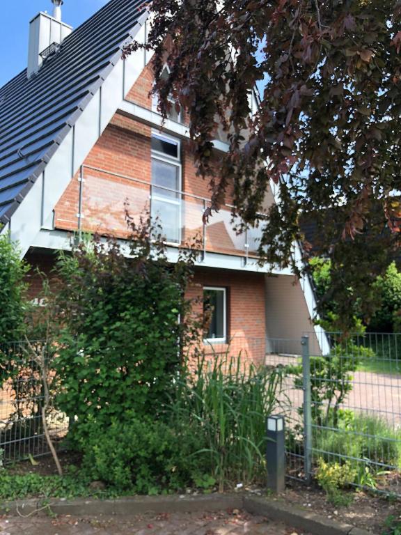 ein rotes Backsteinhaus mit einem Zaun davor in der Unterkunft Schlei 48 in Borgwedel