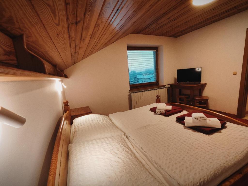 a bedroom with a large white bed with a wooden ceiling at Rooms and Apartments Panker in Moravske-Toplice