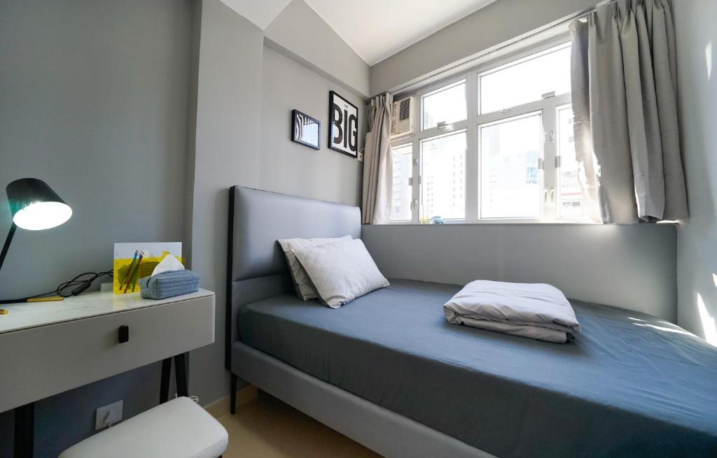 ein kleines Schlafzimmer mit einem blauen Bett und einem Fenster in der Unterkunft Student Accommodation - 294 Hennessy Road in Hongkong