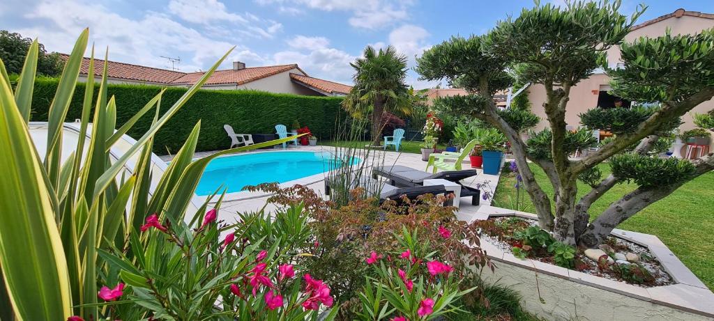 una piscina en un patio con flores y plantas en Chambre privée entrée indépendante piscine familiale chauffée, 4 min du Puy du Fou, en Les Épesses