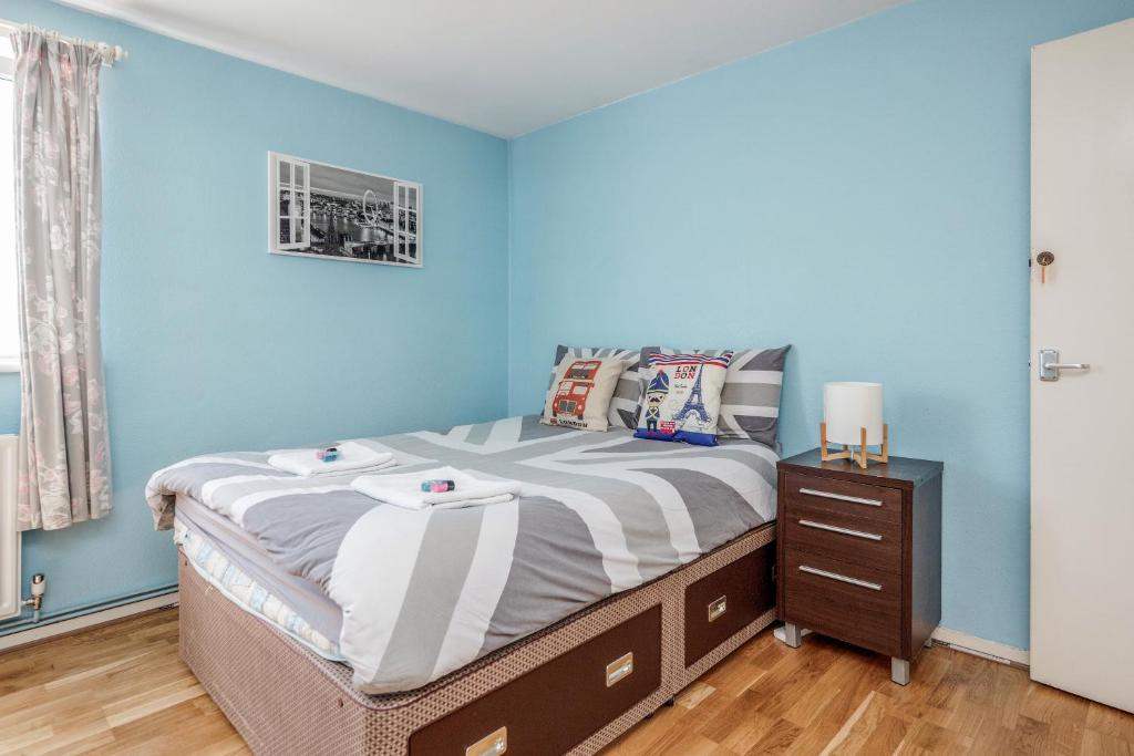 Schlafzimmer mit blauen Wänden, einem Bett und einem Nachttisch in der Unterkunft 4-bedroom flat near BigBen,Parliament & London Eye in London