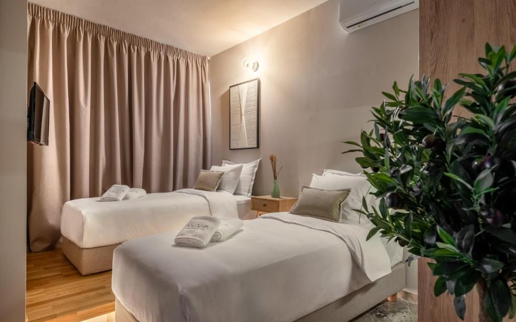 a hotel room with two beds and a potted plant at Numa Suites & Lofts Athens in Athens