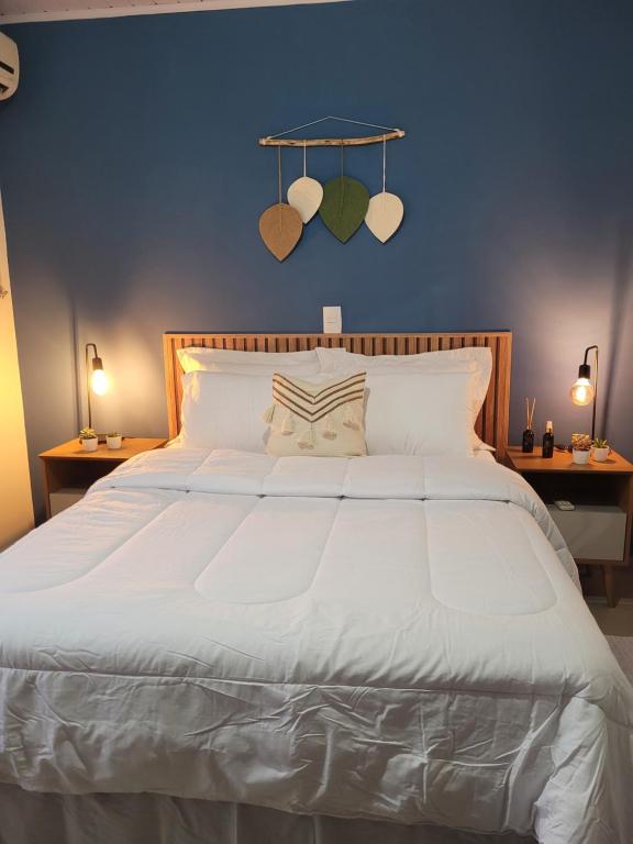 um quarto com uma grande cama branca e uma parede azul em Sobrado em ótima localização. em Criciúma