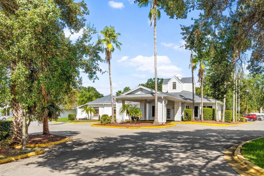 a white house with palm trees on a street at Developer Inn Maingate, a Baymont by Wyndham in Kissimmee