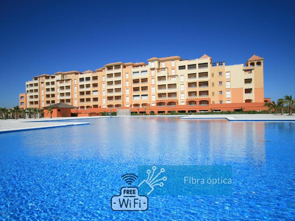 un gran edificio frente a una gran piscina en ISLA CANELA PLAYA Y GOLF, 1ª Línea de playa en Isla Canela