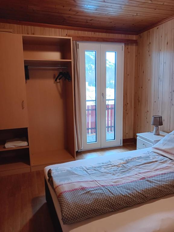 a bedroom with a bed and a large window at Pension Waldegg - restaurant in Saas-Almagell