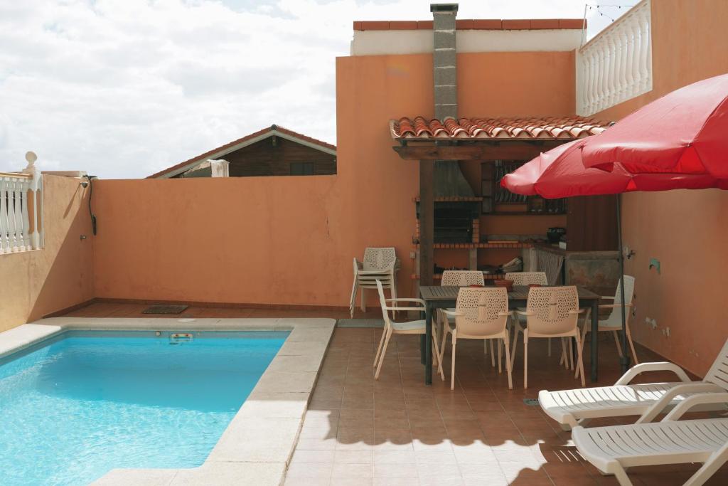 uma piscina com cadeiras, uma mesa e um guarda-sol em Casa Morales em Igueste