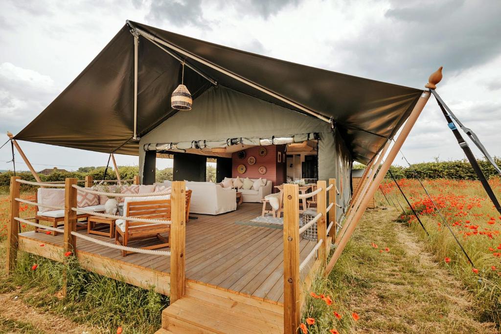 a tent with a deck in a field of flowers at Finest Retreats - Foxley Lodge in Little Walsingham