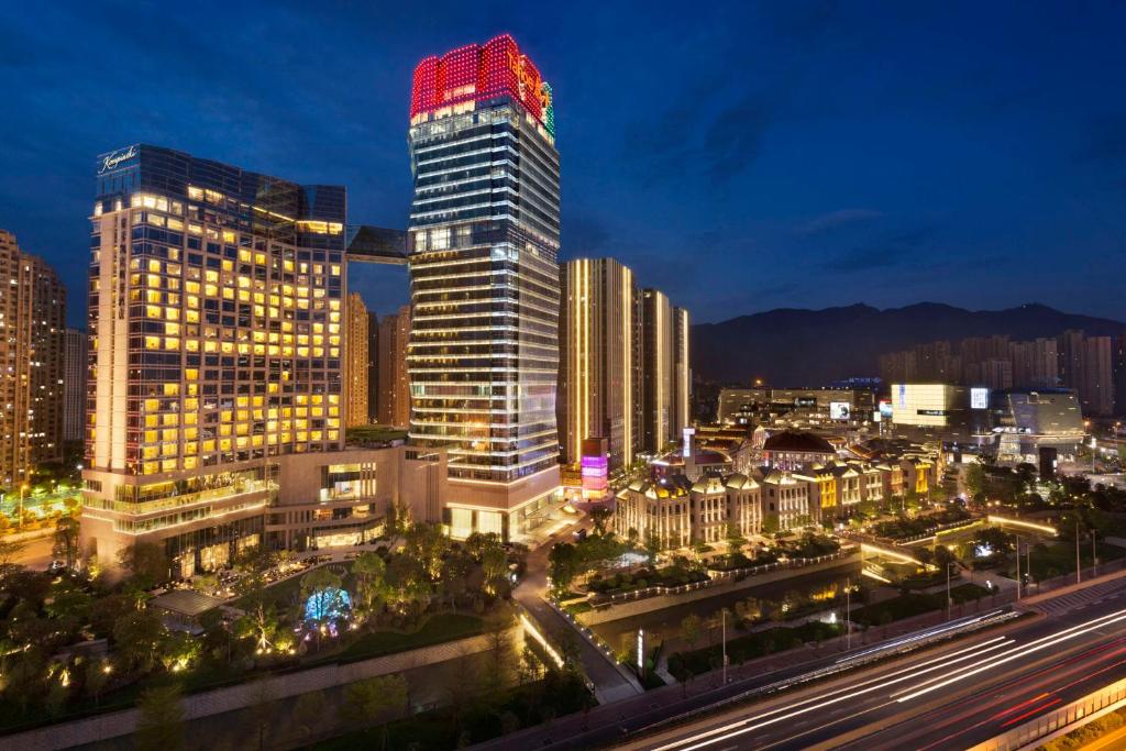Kempinski Hotel Fuzhou في فوتشو: أفق المدينة في الليل مع مبنى طويل