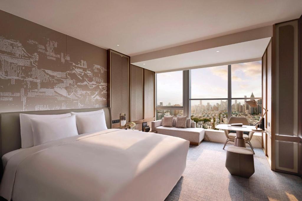 a bedroom with a large white bed and a large window at Kempinski Hotel Nanjing in Nanjing