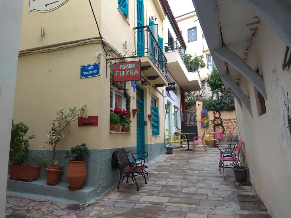 an alley with chairs and tables and a sign on a building at Filyra Pension in Nafplio