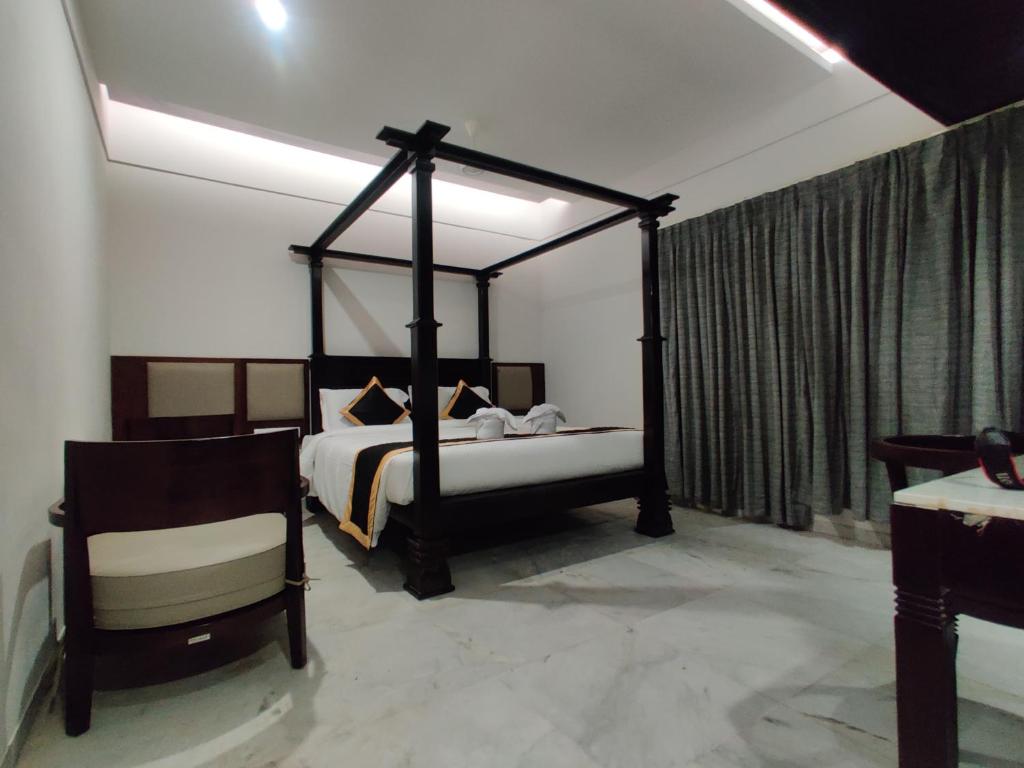 a bedroom with a canopy bed and a chair at Hotel Saratharajans in Madurai