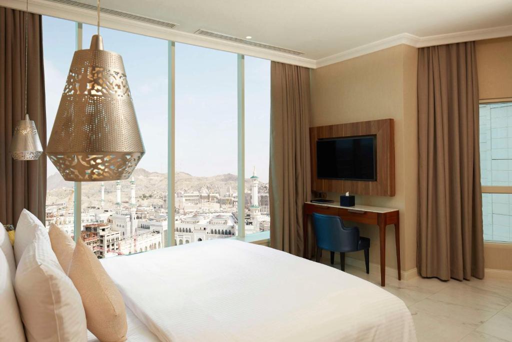 um quarto de hotel com uma cama e uma grande janela em Shaza Makkah em Meca