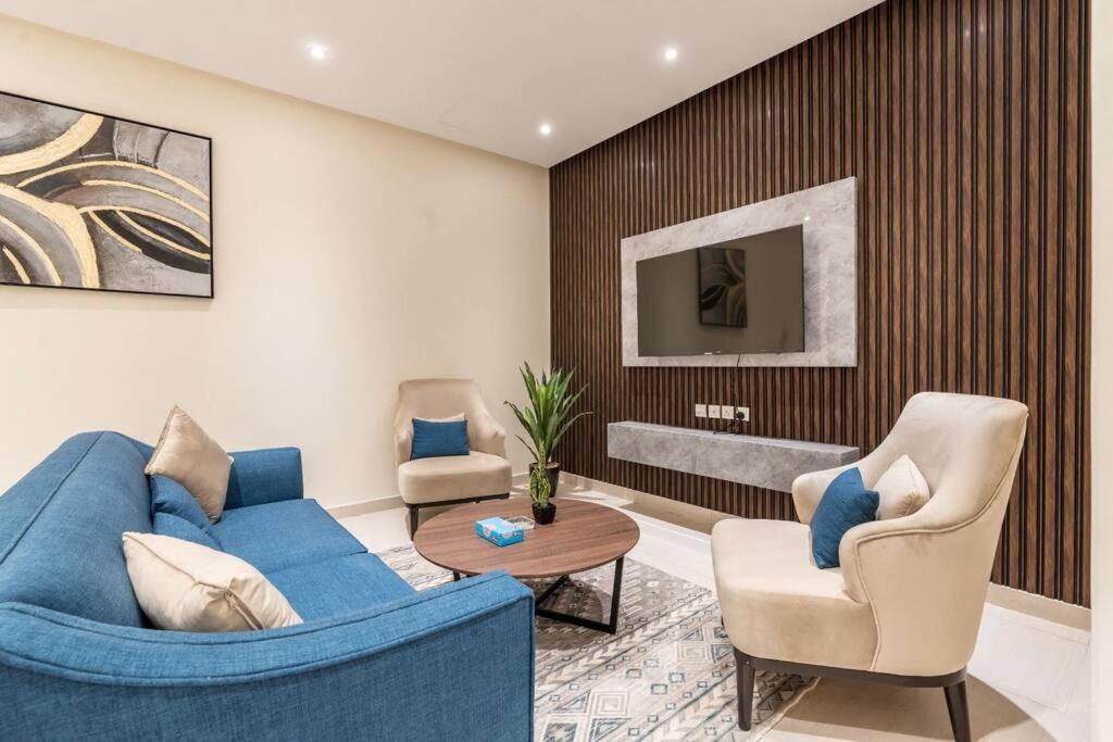 uma sala de estar com um sofá azul e duas cadeiras em Nuzul R141 - Elegant Apartment em Riyadh