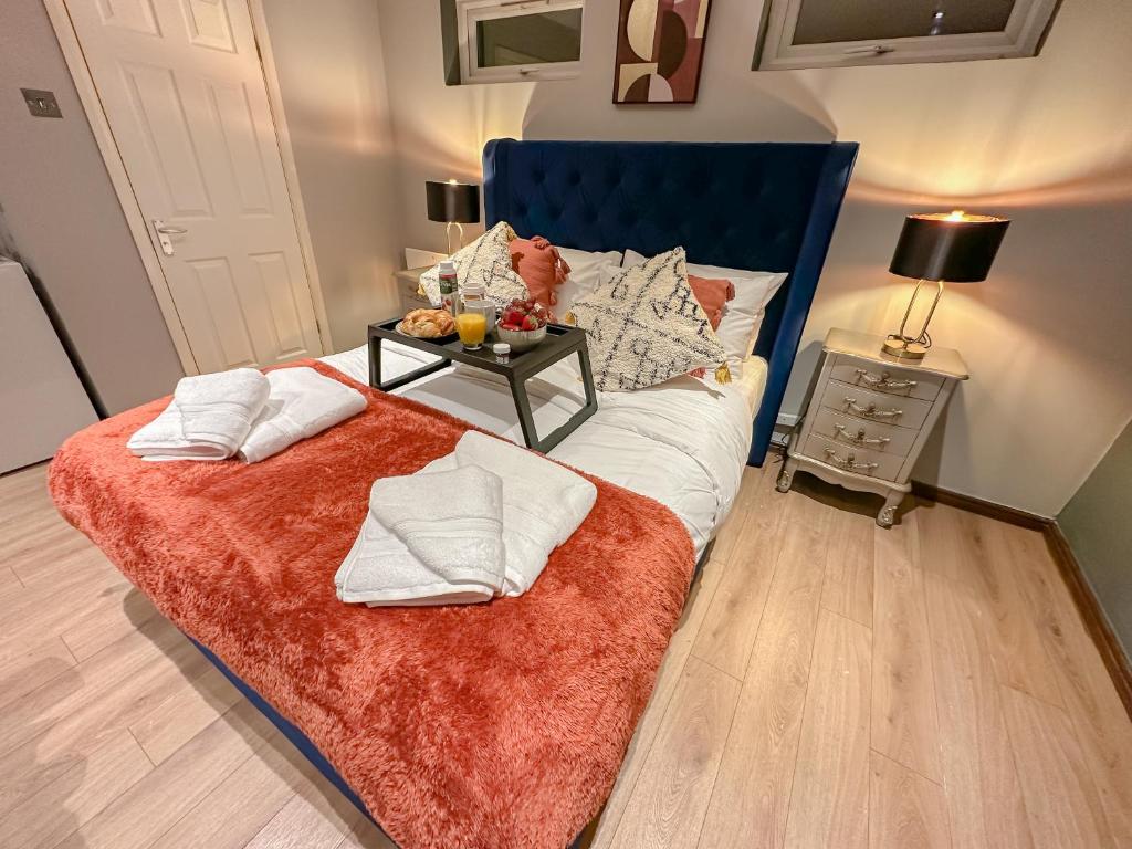 a bedroom with a bed with a blue headboard and a table at Stunning Studio Garden House - Free Wifi & Parking in Hendon