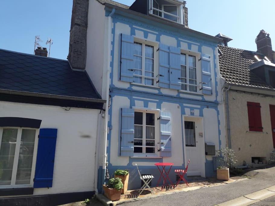 une maison bleue et blanche avec deux chaises rouges à l'extérieur dans l'établissement Maison de pêcheur Souffle de Mer, à Saint-Valery-sur-Somme