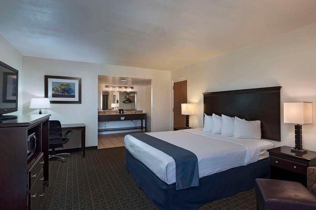 a hotel room with a large bed and a desk at Stevens Inn a Howard Johnson by Wyndham in Carlsbad