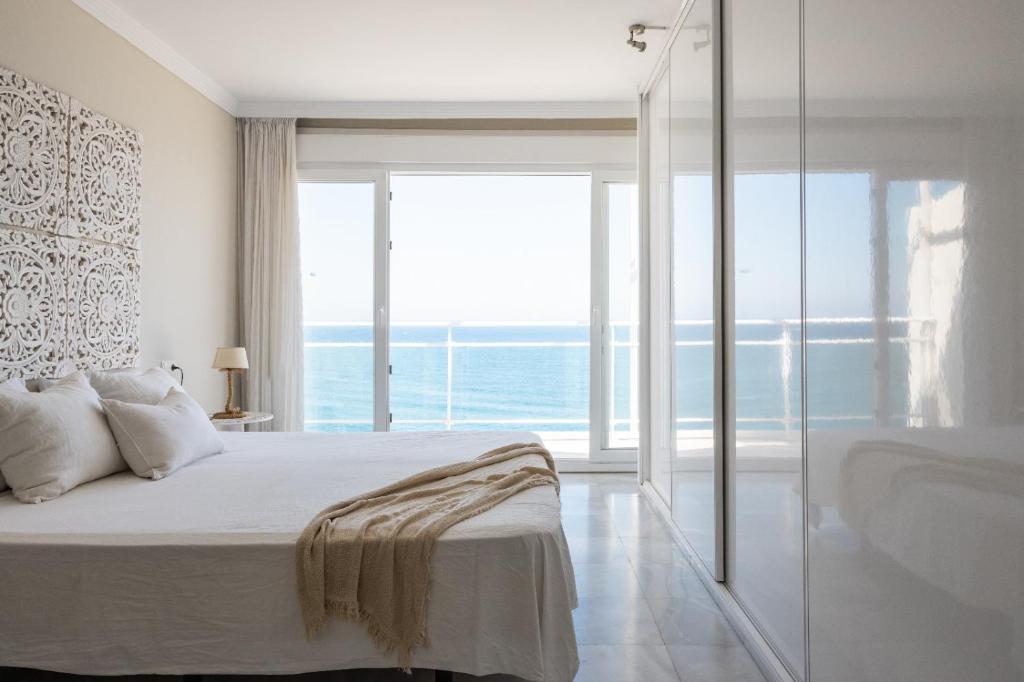 ein Schlafzimmer mit einem Bett und einem großen Fenster in der Unterkunft Maria Paola penthouse aan het strand in Fuengirola